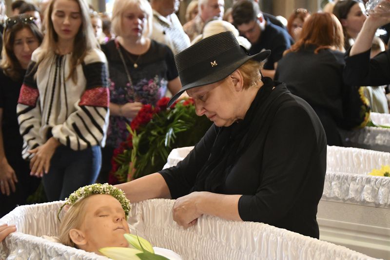 A relative mourns at the coffins of Yaroslav Bazylevych's family members during their funeral service in the Garrison Church in Lviv, Ukraine, Friday, Sept. 6, 2024. Bazylevych's wife Yevgenia and their three daughters - Darina, 18, Emilia, 7, and Yaryna, 21 - were killed in Wednesday's Russian missile attack. (AP Photo/Mykola Tys)