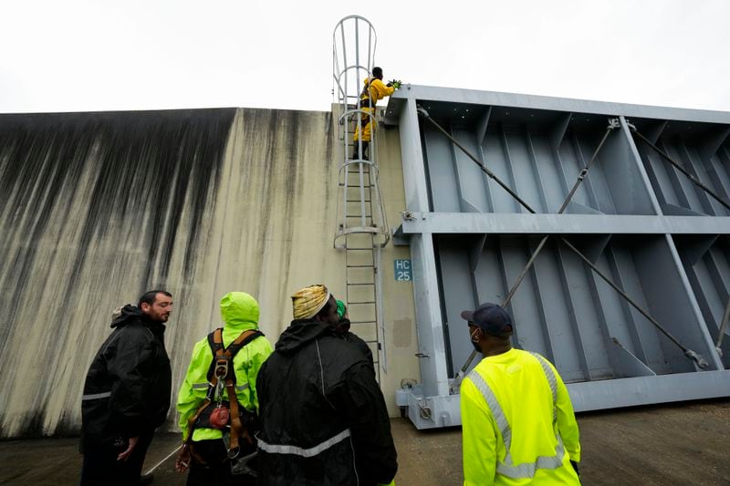 Workers from the Southeast Louisiana Flood Protection Authority-West close floodgates along the Harvey Canal, just outside the New Orleans city limits, in anticipation of Tropical Storm Francine, in Harvey, La., Tuesday, Sept. 10, 2024. (AP Photo/Gerald Herbert)