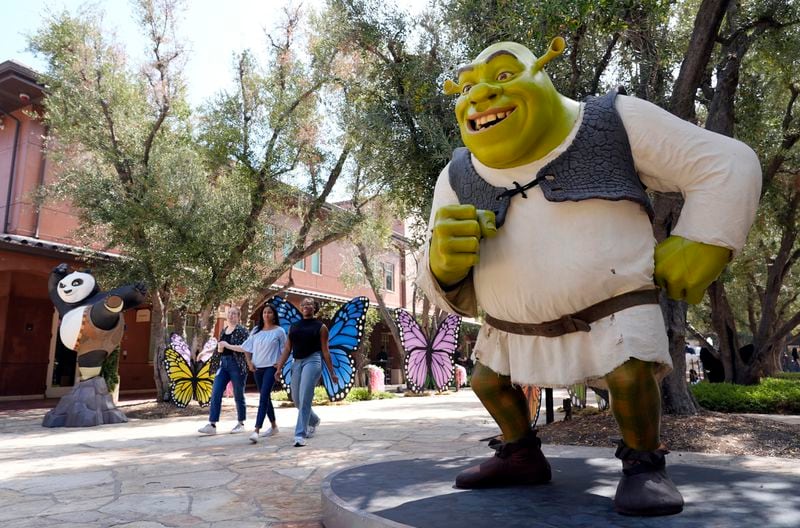 DreamWorks employees walk past statues of animated characters Shrek, from the "Shrek" franchise, right, and Po, from the "Kung Fu Panda" franchise, at the DreamWorks Animation campus, Wednesday, Sept. 25, 2024, in Glendale, Calif. (AP Photo/Chris Pizzello)