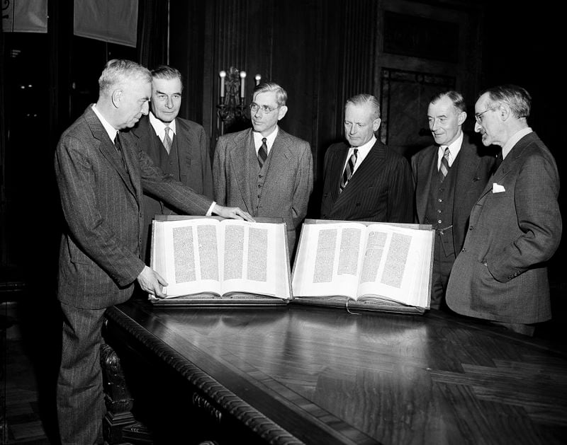 FILE - Members of the New York Public Library Board of Trustees pose for a photo with the first Gutenberg Bible to reach the U.S. 100 years prior, before it is placed on display in the lobby of the New York Public Library on Nov. 7, 1947. From left are Morris Hadley, Junius S. Morgan, Ralph A. Beals, Henry C. Taylor, Roland L. Redmond, and Dr. Albert Berg. The Bible was bought by book collector James Lenox for what was then considered the "mad" price of $2,600. (AP Photo/Ed Ford, File)