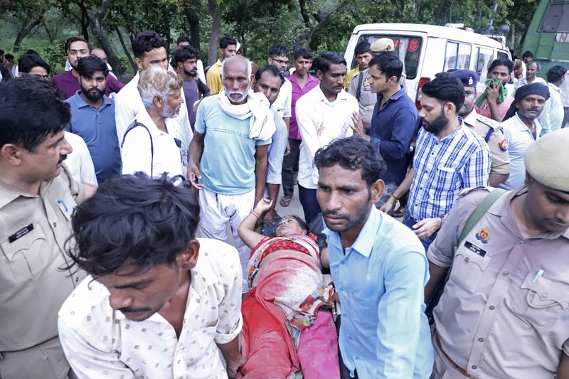 People carry a woman on a stretcher outside the Sikandrarao hospital in Hathras district about 350 kilometers (217 miles) southwest of Lucknow, India, Tuesday, July 2, 2024. At least 60 people are dead and scores are injured after a stampede at a religious gathering of thousands of people in northern India, officials said Tuesday.(AP Photo/Manoj Aligadi)