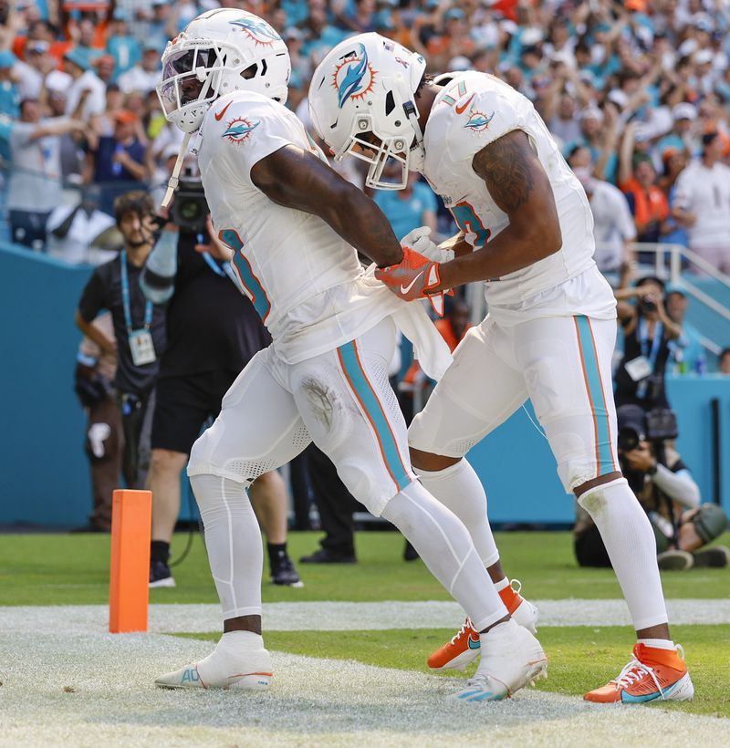 Miami Dolphins wide receiver Tyreek Hill (10) holds his hands behind his back as if he is handcuffed as Miami Dolphins wide receiver Jaylen Waddle (17) unlocks them after Hill scores against the Jacksonville Jaguars in the second half during an NFL football game at Hard Rock Stadium in Miami Gardens, Florida, on Sunday, Sept. 8, 2024. (Al Diaz/Miami Herald via AP)