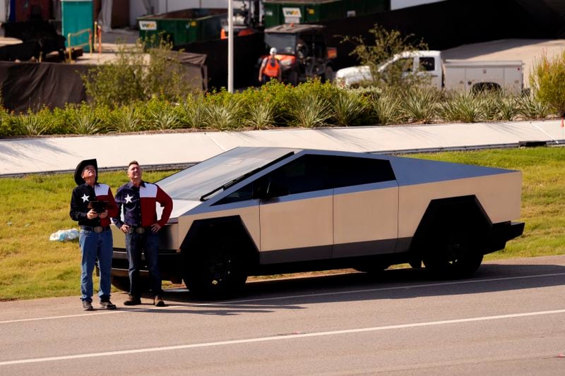 Men wearing Texas flag themed western shirts stand next to a Tesla Cybertruck at the Tesla Gigafactory, Thursday, June 13, 2024, in Austin, Texas. Tesla shareholders are charting the future of the electric vehicle company as they wrap up voting whether or not to restore CEO Elon Musk's massive pay package that was thrown out by a Delaware judge.(AP Photo/Eric Gay)