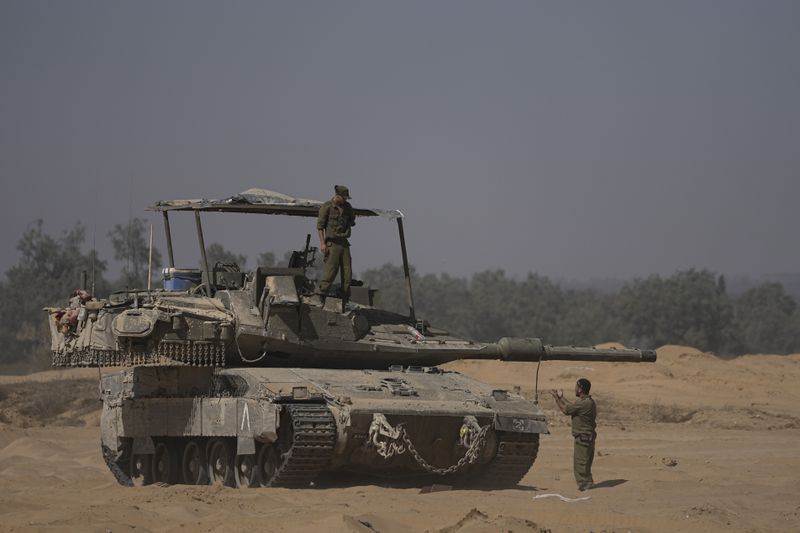 Israeli soldiers work on their tank near the Israel-Gaza border in southern Israel, Wednesday, June 12, 2024. (AP Photo/Tsafrir Abayov)