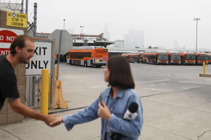 News media prepare to go live in front of a Los Angeles MTA bus depot near the site where overnight a bus was hijacked by an armed subject with passengers on board Wednesday, Sept. 25, 2024, in Los Angeles. One person was fatally shot before police apprehended the suspect. (AP Photo/Ryan Sun)