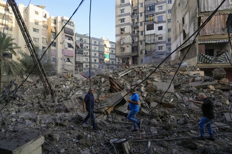 People check damaged buildings at the site of an Israeli airstrike in Dahiyeh, Beirut, Lebanon, Friday, Oct. 4, 2024. (AP Photo/Hassan Ammar)