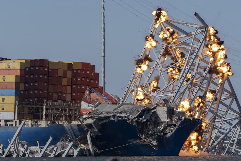 FILE - Explosive charges are detonated to bring down sections of the collapsed Francis Scott Key Bridge resting on the container ship Dali, May 13, 2024, in Baltimore. The main shipping channel into Baltimore's port has fully reopened to its original depth and width following the March 26 collapse of the Francis Scott Key Bridge. (AP Photo/Mark Schiefelbein, File)