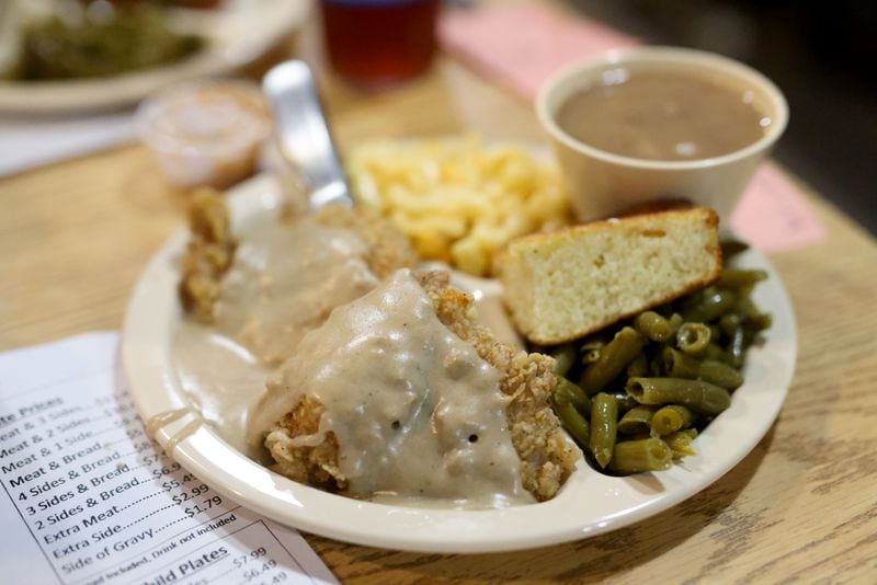 Fried porkchops with gravy is shown with three sides, pinto beans, baked macaroni and cheese, and green beans, at Doug’s Place on Old Allatoona Road, Thursday, November 3, 2022, in Emerson, Ga. (Jason Getz / Jason.Getz@ajc.com)