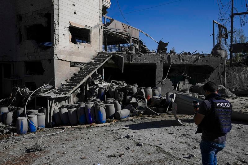 A journalist documents the damaged buildings at the site of an Israeli airstrike, in the village of Temnin, Bekaa Valley, eastern Lebanon, Saturday, Oct. 5, 2024. (AP Photo/Hassan Ammar)