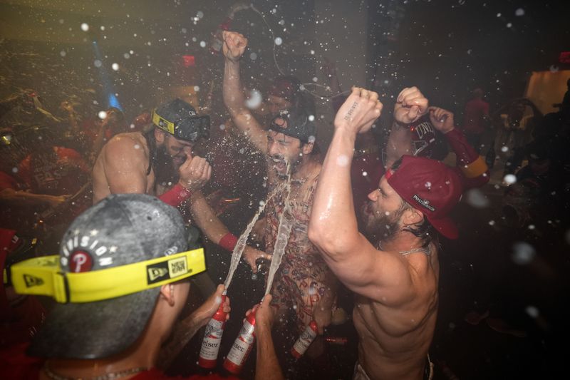 Philadelphia Phillies' Brandon Marsh, from left, Garrett Stubbs and Bryce Harper celebrate after the Phillies won a baseball game against the Chicago Cubs to clinch the NL East title, Monday, Sept. 23, 2024, in Philadelphia. (AP Photo/Matt Slocum)