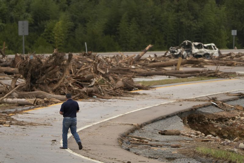 A person walks on Interstate 26 as debris covers the roadway in the aftermath of Hurricane Helene, Friday, Oct. 4, 2024, in Erwin, Tenn. (AP Photo/Jeff Roberson)