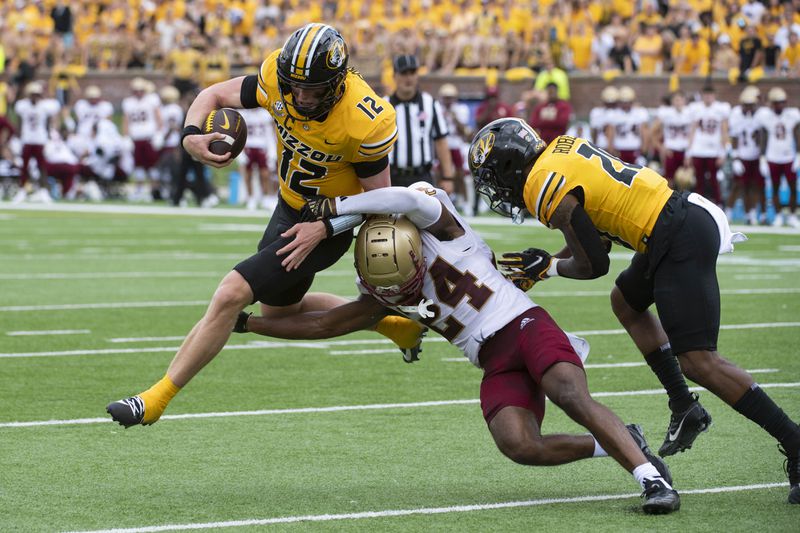 Missouri quarterback Brady Cook (12) jumps over Boston College cornerback Amari Jackson (24) Jamal Roberts, right blocks during the second half of an NCAA college football game, Saturday, Sept. 14, 2024, in Columbia, Mo. Brady scored on the play. (AP Photo/L.G. Patterson)