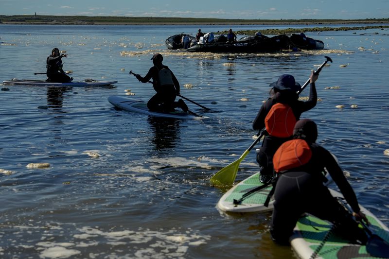 Erin Greene, left, owner of Sup North, directs a person while leading a paddleboarding tour, Thursday, Aug. 8, 2024, in Churchill, Manitoba. (AP Photo/Joshua A. Bickel)