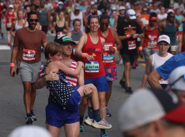 Young runner gets assist at the finish of the 55th running of the Atlanta Journal-Constitution Peachtree Road Race in Atlanta on Thursday, July 4, 2024.   (Jason Getz / AJC)