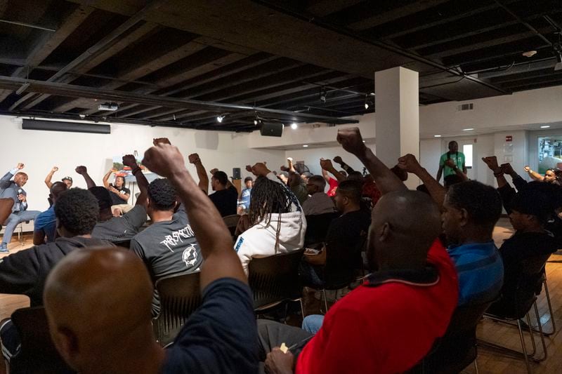 Panelists and attendees raise their fists during a Black Man Lab meeting to discuss the candidacy of Vice President Kamala Harris, Monday, July 22, 2024, in Atlanta. The Black Man Lab hosts weekly gatherings with the purpose of providing an intergenerational safe space for Black men and boys. (AP Photo/Stephanie Scarbrough)