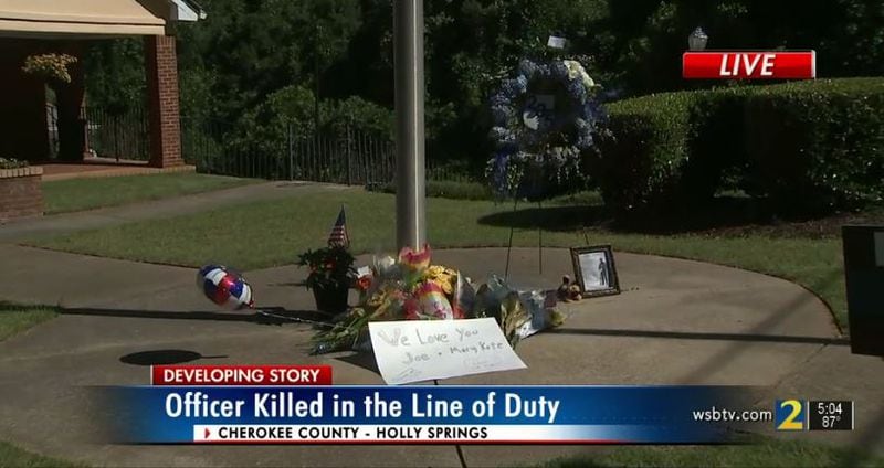 Mourners left flowers, a wreath and a poster outside Holly Springs police headquarters following the young officer's death.