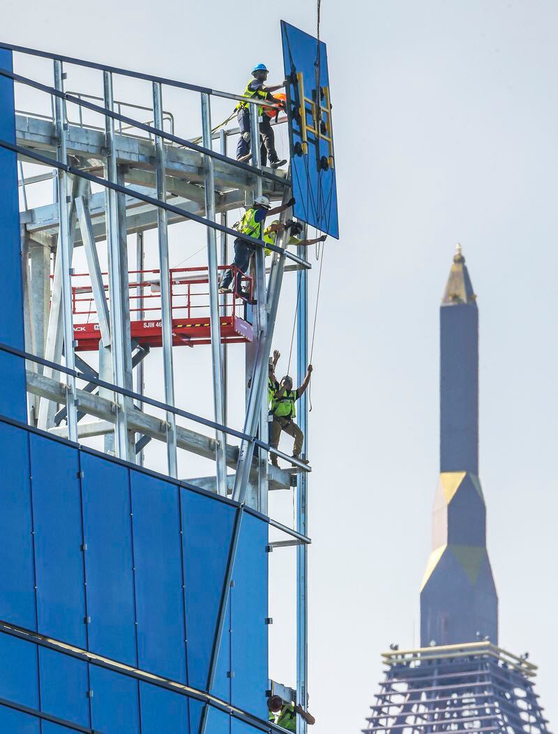 Construction has still not reached its pre-recession peaks, but the sector has grown solidly. Here a picture of workers moving glass into place on the new corporate headquarters for NCR last year.	JOHN SPINK/JSPINK@AJC.COM.