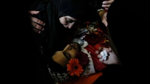 The mother of Ahmed Nidal Aslan, who was killed during clashes with Israeli forces, mourns over the body of her son during his funeral in the West Bank refugee camp of Qalandiya, Wednesday, July 24, 2024. The Palestinian health ministry said a man was shot dead Wednesday by Israeli fire in the central West Bank, as violence flares in the Israeli occupied territory. (AP Photo/Mahmoud illean)