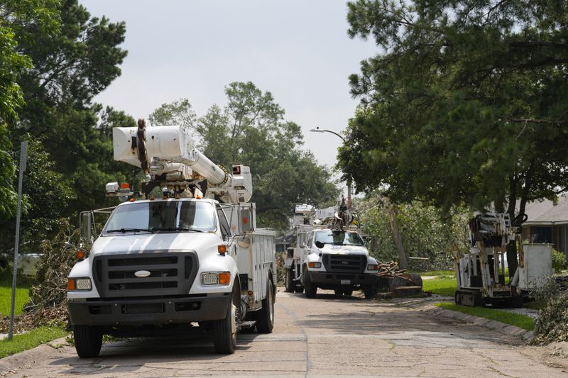 Utility trucks line Grovewood Lane to assist recovery from last week's severe storms, Tuesday, May 21, 2024, at Timbergrove in Houston. (Yi-Chin Lee/Houston Chronicle via AP)