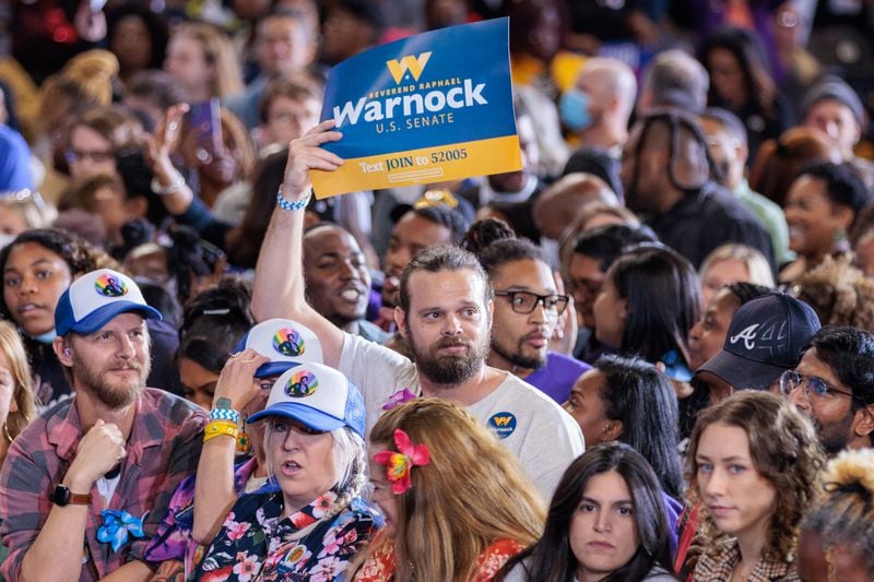 A supporter of U.S. Sen. Raphael Warnock holds at poster at an October event in Atlanta where Warnock was joined on stage by former President Barack Obama. (Arvin Temkar/AJC)
