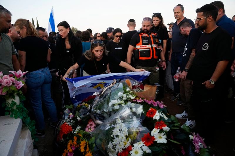 A mourner lays an Israeli flag on the grave of slain hostage Alexander Lobanov, who was killed in Hamas captivity in the Gaza Strip, in Ashkelon, southern Israel, Sunday, Sept. 1, 2024. (AP Photo/Tsafrir Abayov)