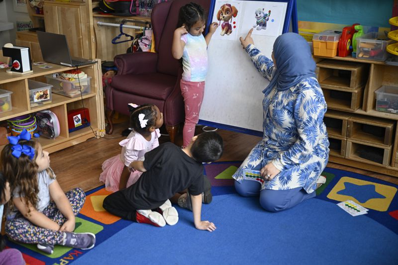 Preschool teacher Tinhinane Meziane, right, instructs to her students on how to vote the most popular character of the TV show PAW Patrol at the ACCA Child Development Center, Thursday, Sept. 19, 2024, in Annandale, Va. The students are getting foundational lessons on how to live in a democracy by allowing them to regularly vote on different things through out the day. (AP Photo/John McDonnell)