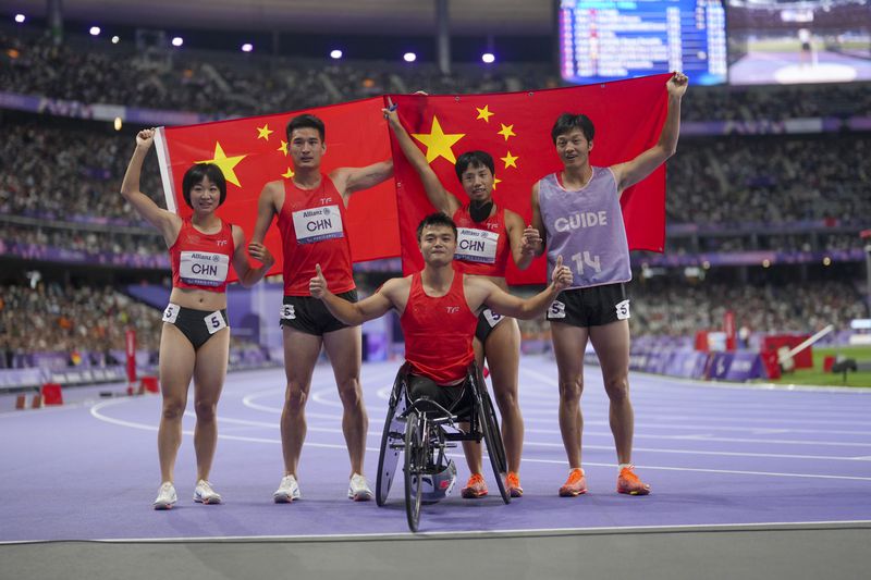 China team poses after winning the gold and setting a new world record in the 4x100 m. universal relay at the 2024 Paralympics, Friday, Sept. 6, 2024, in Paris, France. From left, Wen Xiaoyan, Wang Hao, Hu Yang and Zhou Guohua, with her guide. (AP Photo/Thibault Camus)