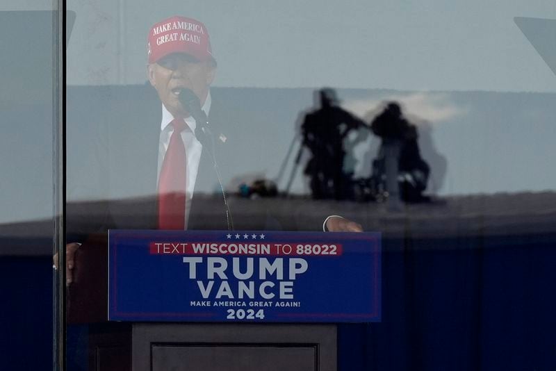 Law enforcement snipers appear in the reflection of bullet-resistant glass as Republican presidential nominee former President Donald Trump speaks during a campaign rally at Dodge County Airport, Sunday, Oct. 6, 2024, in Juneau, Wis. (AP Photo/Julia Demaree Nikhinson)