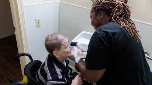 Employee Von Freeman helps resident Jeffrey Clarke clean up after dinner in a group home for people with disabilities in Tucker on Wednesday, November 9, 2022.   (Arvin Temkar / arvin.temkar@ajc.com)