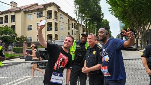 Atlanta police Chief Darin Schierbaum poses for a photo with one of his officers and two Peachtree Road Race participants.