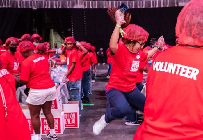 Ivy Maxwell, jumps in excitement with the completion of a box of red lentil jambalaya kits for local food banks.  Volunteers of all ages filled up five shifts of more than 1000 people.  (Jenni Girtman for The Atlanta Journal-Constitution)