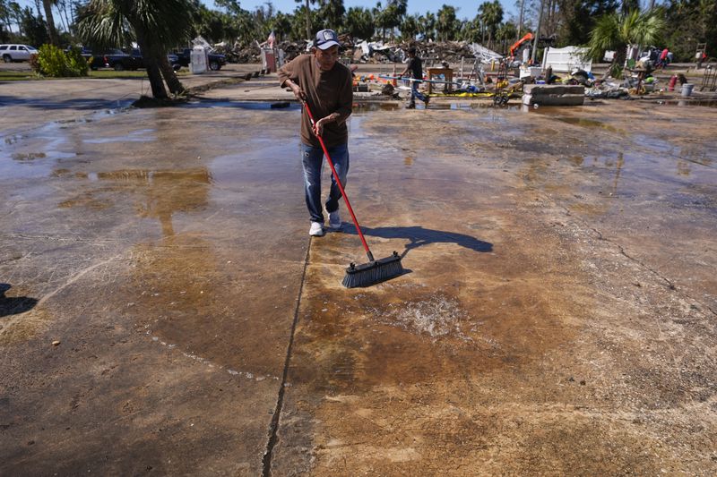 Workers clean up a dock where a boat shed was destroyed in the aftermath of Hurricane Helene, in Jena, Fla., Sunday, Sept. 29, 2024. (AP Photo/Gerald Herbert)