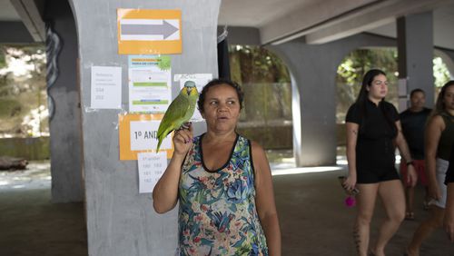 Tereza Domingos holds her parrot Noninho after voting in the municipal elections in Rocinha, Rio de Janeiro, Sunday, Oct. 6, 2024. (AP Photo/Bruna Prado)