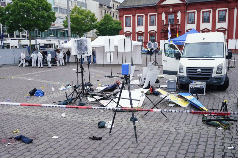 Forensics officers stand behind a smashed stall on the market square in Mannheim, Germany, Friday, May 31, 2024. An assailant with a knife attacked and wounded several people in a central square in the southwestern German city of Mannheim on Friday, police said. Police shot the attacker, who also was hurt. (Uwe Anspach/dpa via AP)
