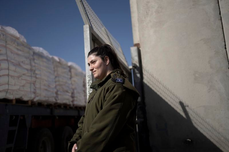 FILE - An Israeli soldier stands guard as trucks carrying humanitarian aid bound for the Gaza Strip leave a holding area at Kerem Shalom Crossing on the intersection of two borders between Egypt and southern Israel and the Gaza Strip and southern Israel, Wednesday, Jan. 10, 2024. A persistent breakdown in law and order is rendering an aid route in south Gaza unusable, the UN and NGOs say, days after Israel's military said it would pause combat there to help aid reach desperate Palestinians. (AP Photo/Maya Alleruzzo, File)
