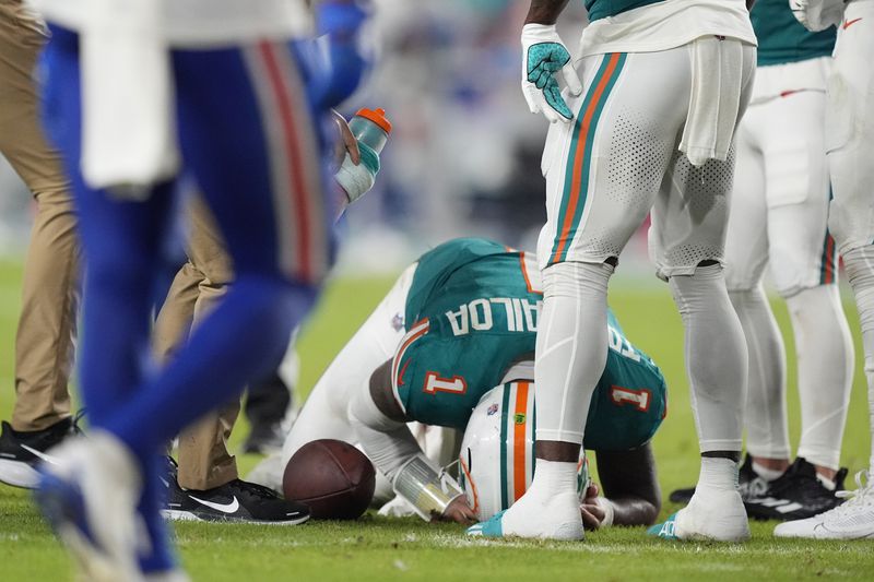 Miami Dolphins quarterback Tua Tagovailoa (1) is assisted on the field during the second half of an NFL football game against the Buffalo Bills, Thursday, Sept. 12, 2024, in Miami Gardens, Fla. (AP Photo/Rebecca Blackwell)