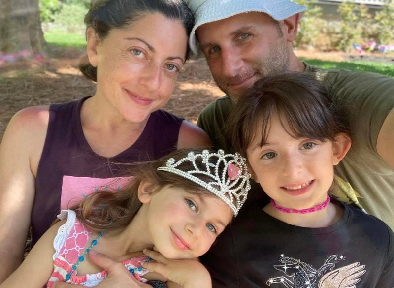 Carey Yaruss Sanders (back left) and her husband Gabriel Sanders (back right) smile for a picture with their two children Dori (front left) and Quinn (front right).