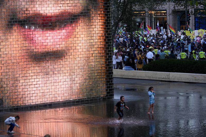 Children play in the water as protesters march prior to the start of the Democratic National Convention Sunday, Aug. 18, 2024, in Chicago.(AP Photo/Julio Cortez)