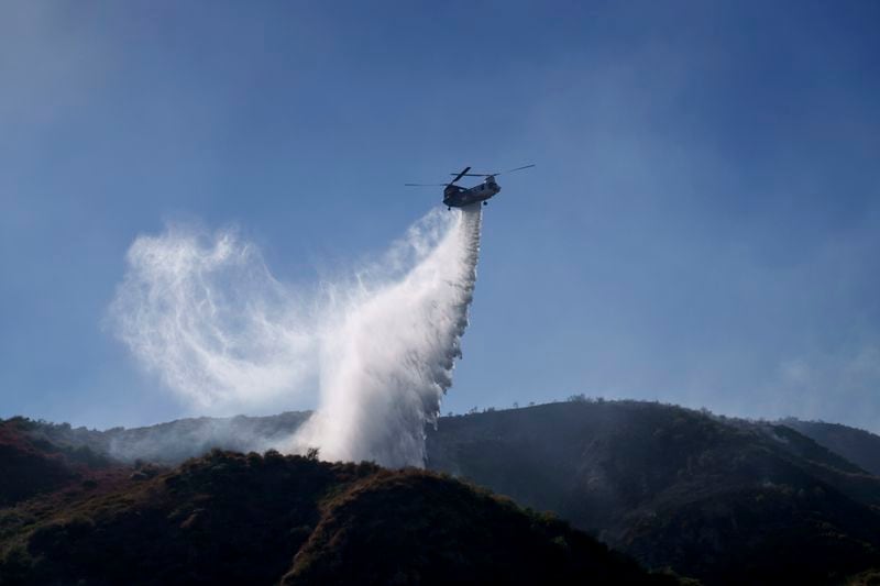 A helicopter drops water on a hillside during the Sharp Fire in Simi Valley, Calif., Wednesday, July 3, 2024. (AP Photo/Eric Thayer)