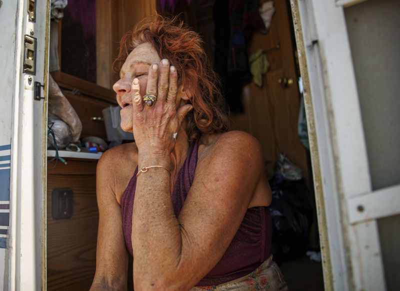 Evacuee Misti Morrow Mosley wipes her face while sitting on the steps of an RV at an evacuation shelter as the Thompson Fire burns, Wednesday, July 3, 2024, in Oroville, Calif. (AP Photo/Ethan Swope)