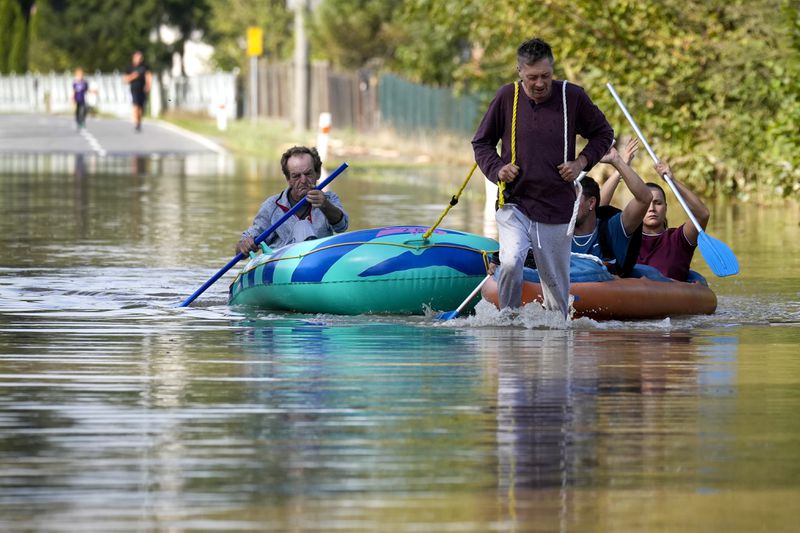 Residents paddle through a flooded street in Bohumin, Czech Republic, Tuesday, Sept. 17, 2024. (AP Photo/Darko Bandic)