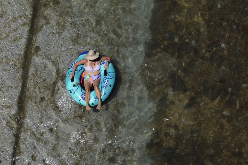 A tuber floats the cool Comal River as temperatures in South Texas hit triple-digit numbers, Wednesday, Aug. 21, 2024, in New Braunfels, Texas. (AP Photo/Eric Gay)