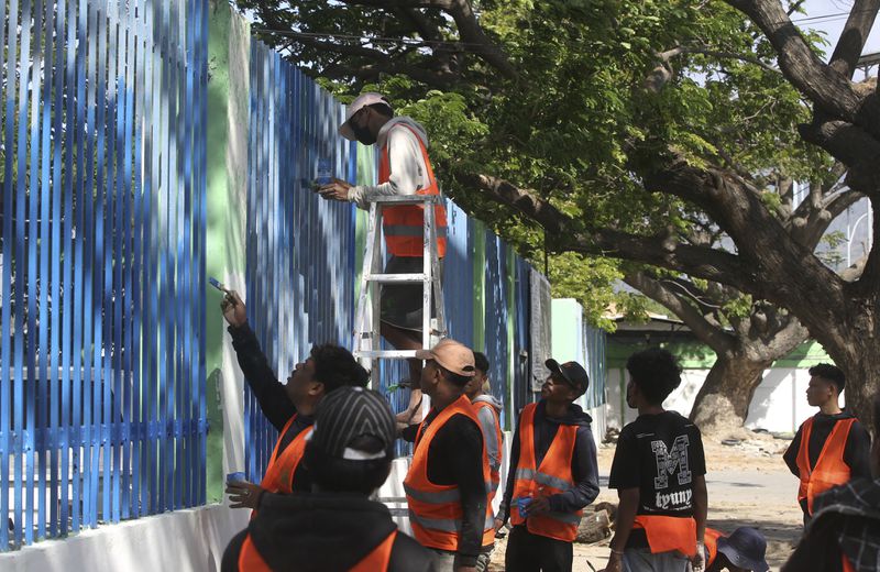 Volunteers paint a fence in preparation of the arrival of Pope Francis in Dili, East Timor, Friday, Sept. 6, 2024. (AP Photo/Firdia Lisnawati)