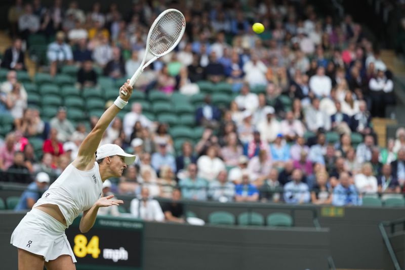 Iga Swiatek of Poland serves to Sofia Kenin of the United States during their first round match at the Wimbledon tennis championships in London, Tuesday, July 2, 2024. (AP Photo/Mosa'ab Elshamy)