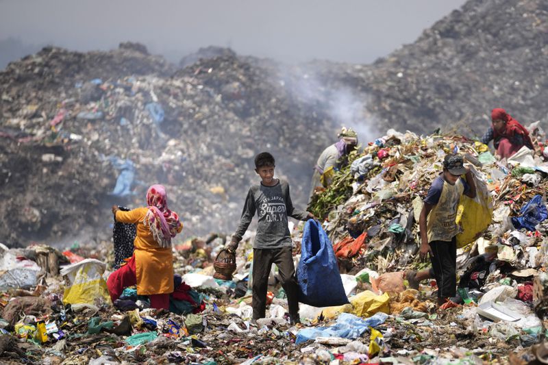 Waste picker Rajdin, 17, looks for recyclable material during a heat wave at a garbage dump on outskirts of Jammu, India, Wednesday, June 19, 2024. As many as 4 million people in India scratch out a living searching through landfills for anything they can sell. (AP Photo/Channi Anand)