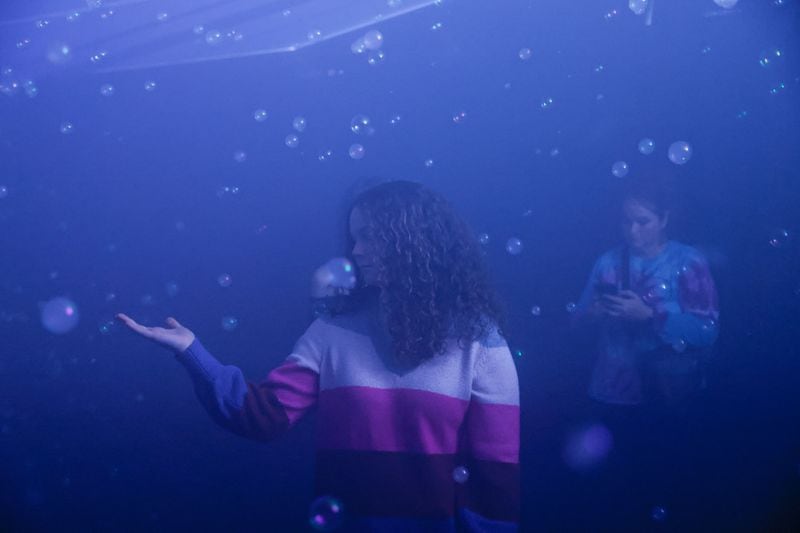 Meme Coleman, 15, plays with smoke bubbles in an installation titled “A Quiet Storm” at Balloon Museum exhibit at Pullman Yards in Atlanta on Monday, Feb. 19, 2024. The exhibit features inflatable installations created by artists from around the world. (Natrice Miller/ Natrice.miller@ajc.com)