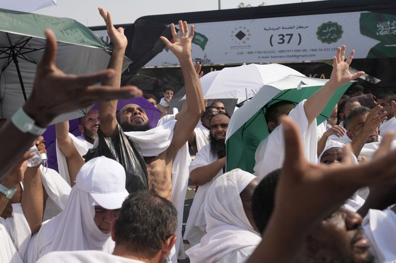 Muslim pilgrims try to reach for free drinking water being distributed in Arafat, on the second day of the annual hajj pilgrimage, near the holy city of Mecca, Saudi Arabia, Saturday, June 15, 2024. Masses of Muslims gathered at the sacred hill of Mount Arafat in Saudi Arabia for worship and reflection on the second day of the Hajj pilgrimage. (AP Photo/Rafiq Maqbool)