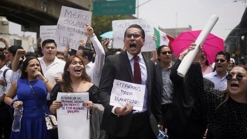 Law students block a street to protest against constitutional reform proposals that would make judges stand for election, outside a sports center where lawmakers are meeting as an alternative due to other demonstrators blocking the Congress building in Mexico City, Tuesday, Sept. 3, 2024. The signs read in Spanish: "Call us to ignore us," and "The future of the next decades in Mexico is being voted on now!" (AP Photo/Felix Marquez)