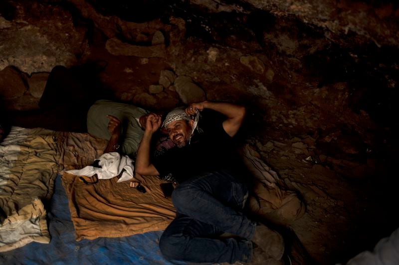 Hassan Battat takes cover from the midday heat in a cave in the West Bank village of Khirbet Zanuta, Tuesday, Aug. 27, 2024. Ten months after settlers threatened to kill them if they didn't leave their village, some Palestinian residents are finally home, under a rare court order. (AP Photo/Maya Alleruzzo)