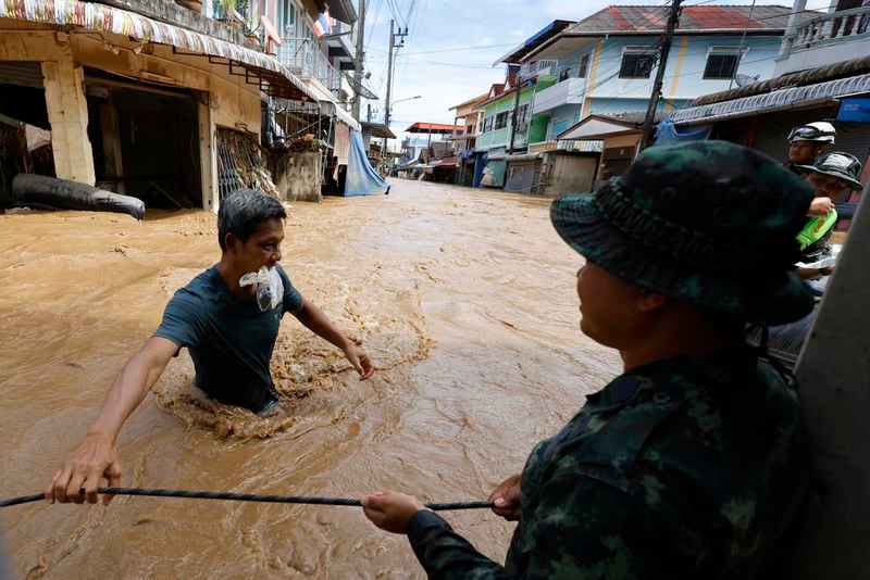 People wade through floodwaters in Chiang Rai Province, Thailand, Friday, Sept. 13, 2024. (AP Photo/Sarot Meksophawannakul)